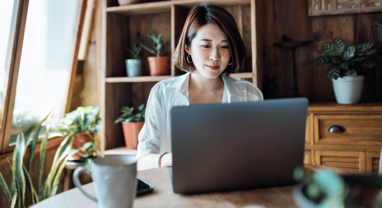 A young woman sits in front of a laptop computer at home in the evening