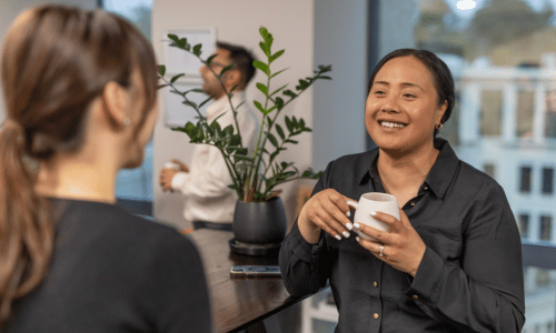 Colleagues chatting over coffee in an office